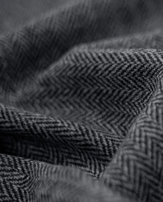 Der Harris Tweed Stoff ist in dunkelgrauem Herringbone Muster gefertigt.