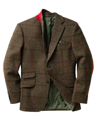 Das Veston mit original Harris Tweed ist von vorne gezeigt. Die Farbe ist ein klassisches Grün mit Strukturkaro. Die Lederflecken an den Ellbogen können problemlos abgenommen werden. Ein besonderer Eyecatcher ist die rote Unterseite des Kragens.