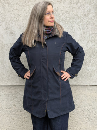 Der Regenmantel ist von vorne zu sehen. Gut sichtbar ist die Liebe zum Detail, die im Schnitt und in der Konfektion liegen. Besonders fällt die Wiener Naht auf, die mit Passerpoil schön verziert ist. 